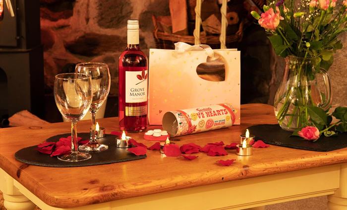Coffee Table with bottle of wine, wine glasses vase with roses and gift